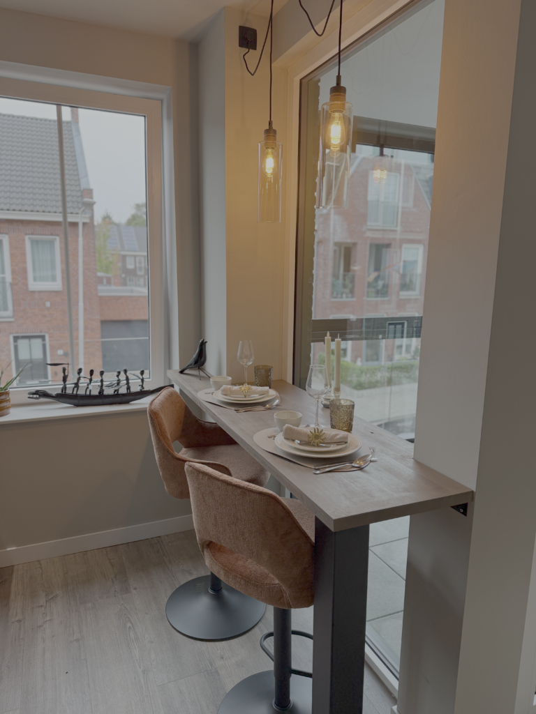 Zwevende tafel aan het raam met terracotta krukken in klein appartement