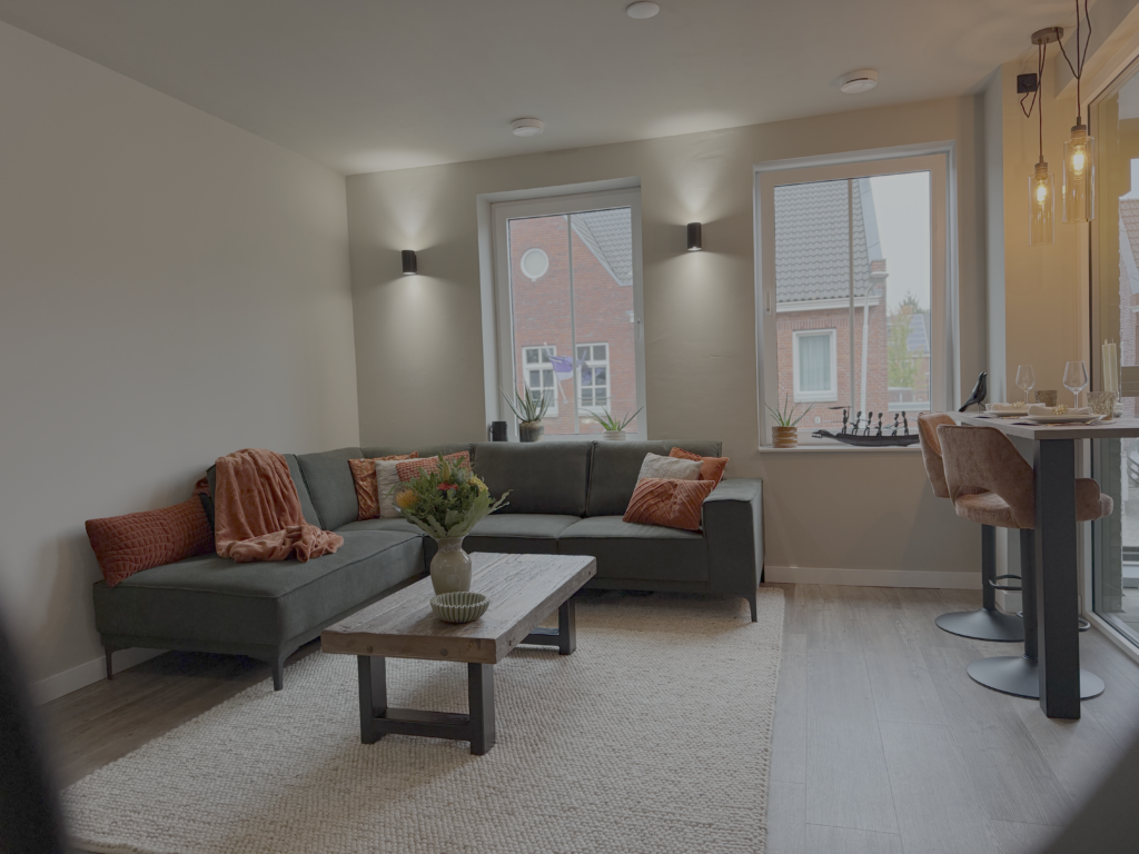 Woonkamer nieuwbouwappartement Zundert met salie groene muur en terracotta accenten